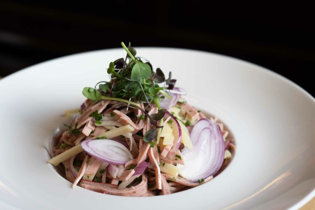 Fein geschnittener Wurstsalat mit roten Zwiebeln und frischen Kräutern.