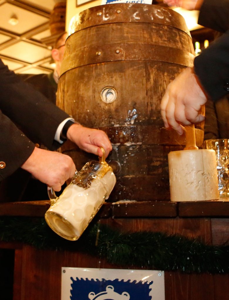 Beim traditionellen Fassanstich wird frisch gezapftes Bier aus einem großen Holzfass in einen Maßkrug gefüllt.
